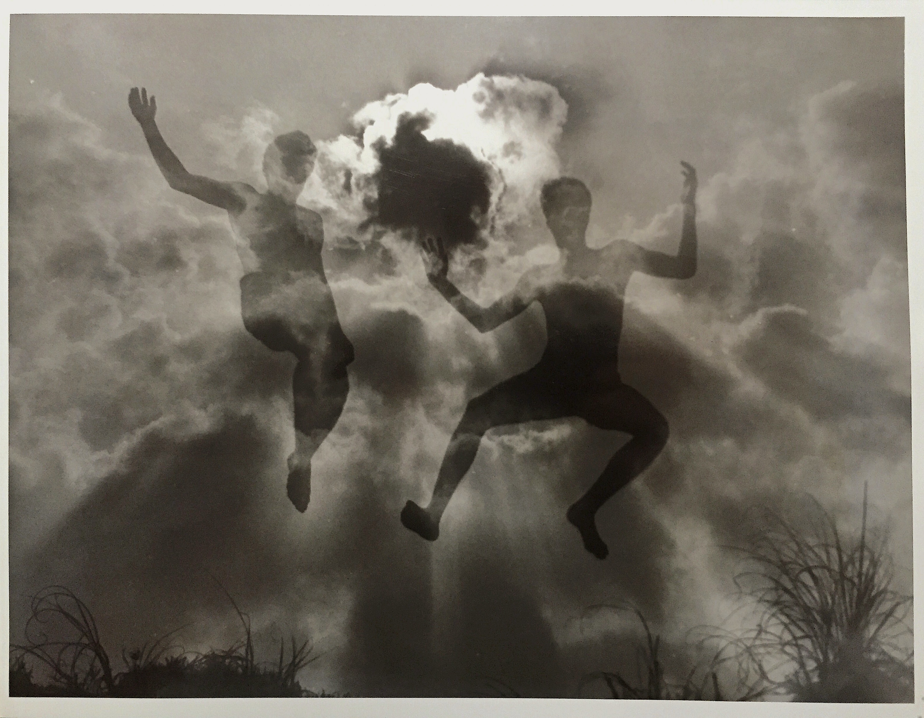 A double exposure of friends in high school jumping off of a sand dune- and clouds